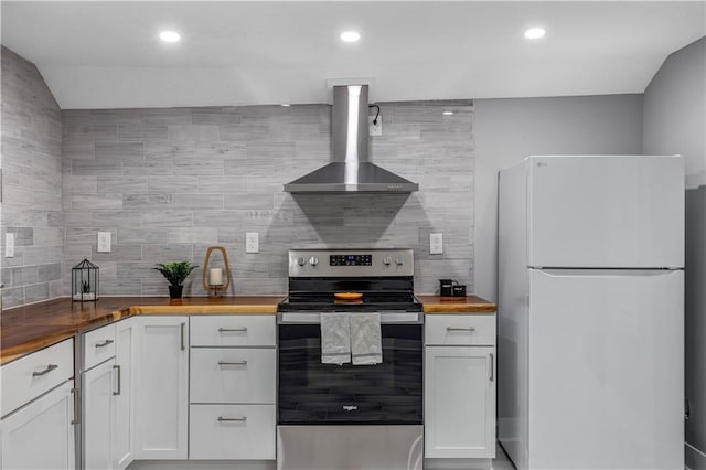 kitchen featuring stainless steel electric range oven, white cabinetry, wood counters, white refrigerator, and wall chimney exhaust hood