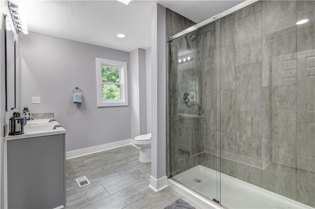 bathroom featuring a shower with door, a textured ceiling, toilet, and vanity