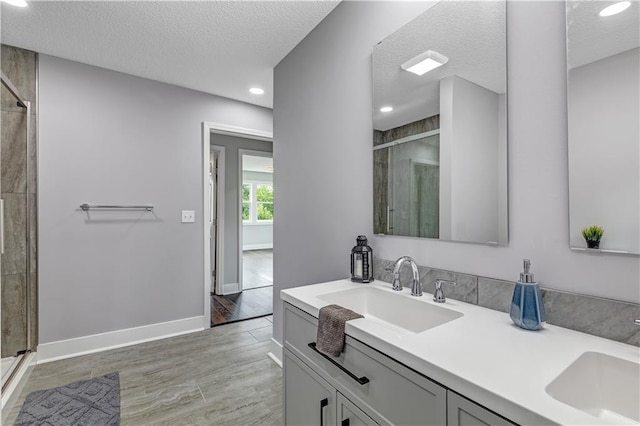 bathroom featuring a textured ceiling, an enclosed shower, and vanity