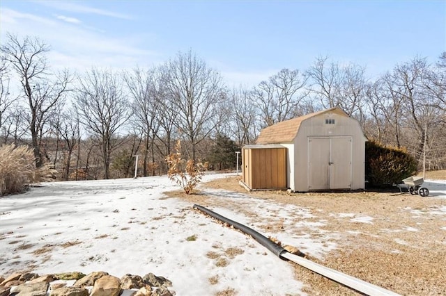 yard layered in snow featuring a shed