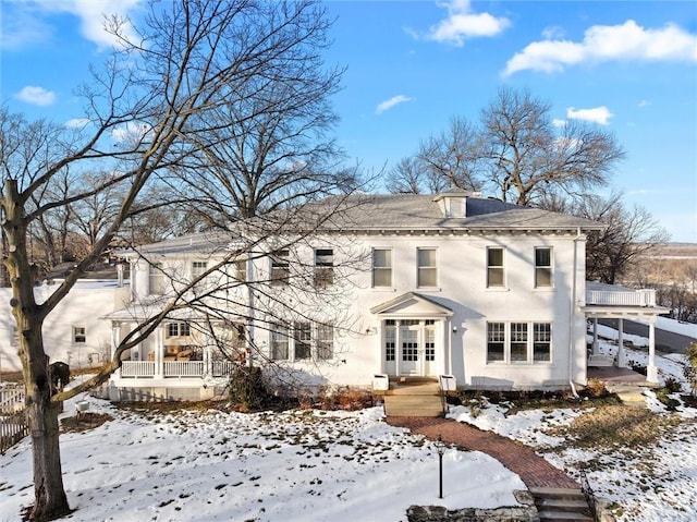 snow covered back of property featuring french doors and covered porch