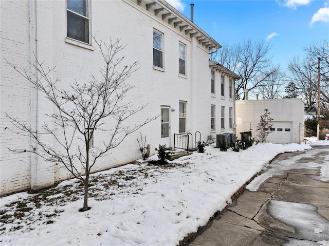 view of snowy exterior with a garage and central air condition unit