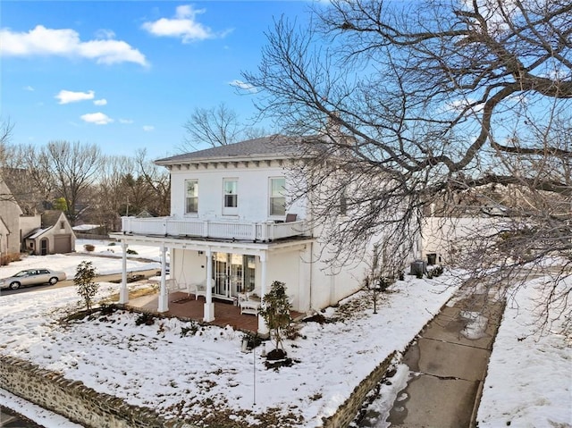 snow covered back of property with a balcony