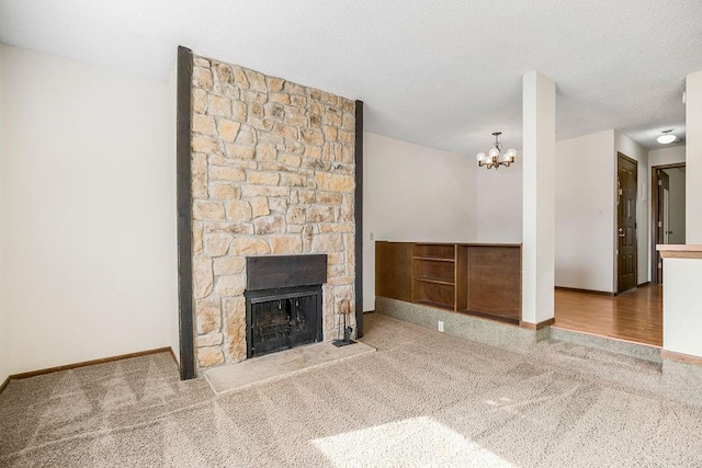 unfurnished living room with carpet floors, a fireplace, a textured ceiling, and a notable chandelier