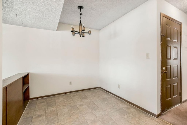 unfurnished dining area featuring a textured ceiling and a chandelier