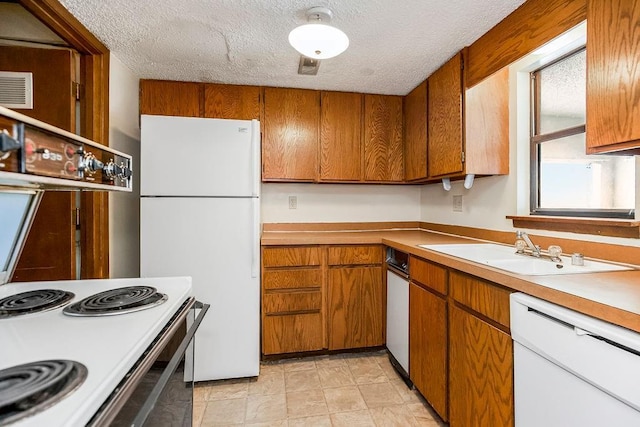 kitchen featuring sink, white appliances, and a textured ceiling