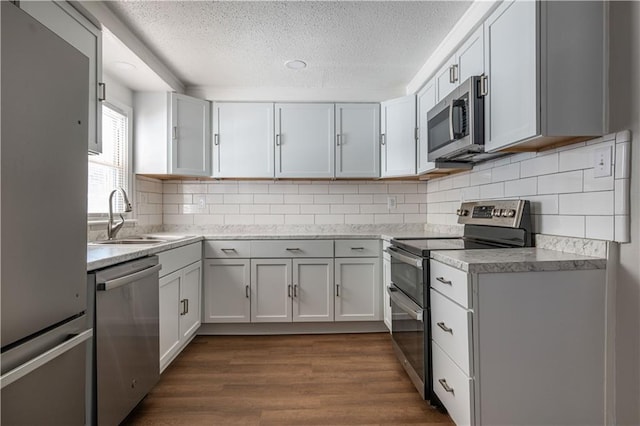 kitchen with sink, white cabinetry, appliances with stainless steel finishes, a textured ceiling, and dark hardwood / wood-style flooring