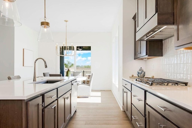 kitchen with tasteful backsplash, sink, an inviting chandelier, hanging light fixtures, and dark brown cabinets