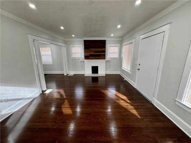 unfurnished living room featuring dark hardwood / wood-style floors, ornamental molding, and a textured ceiling