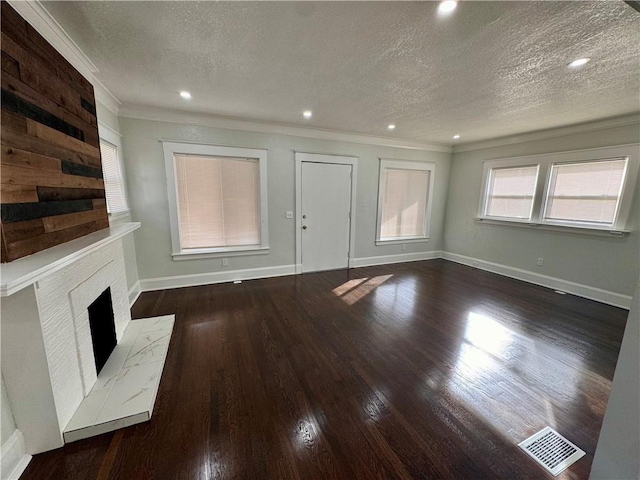 unfurnished living room featuring a textured ceiling, ornamental molding, a fireplace, and dark hardwood / wood-style floors