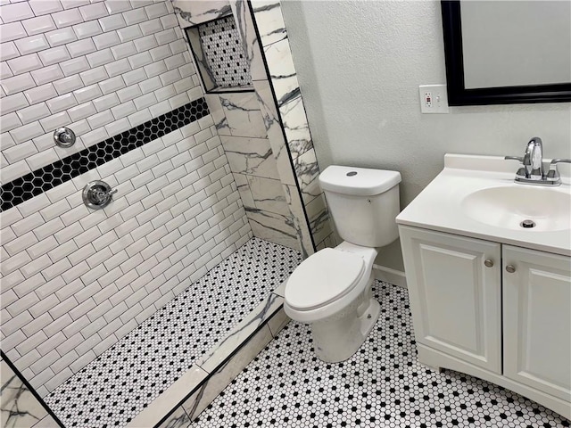 bathroom featuring toilet, vanity, and tiled shower