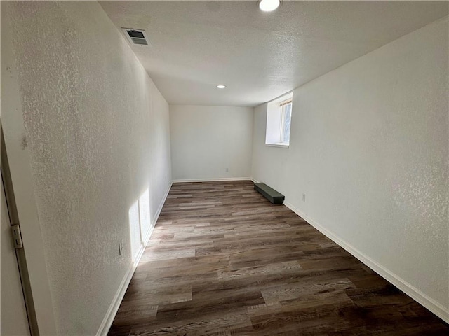 spare room with a textured ceiling and dark hardwood / wood-style floors