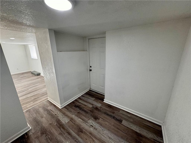 empty room with a textured ceiling and dark hardwood / wood-style floors