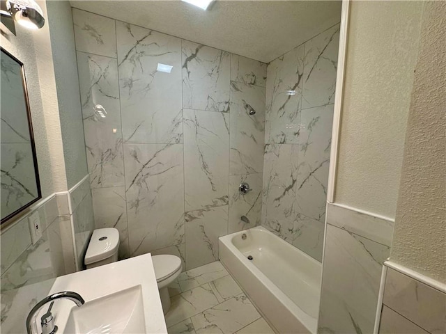 full bathroom featuring toilet, tile walls, sink, and shower / washtub combination