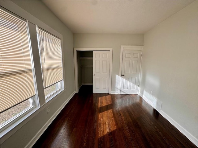 unfurnished bedroom with dark hardwood / wood-style floors and a closet