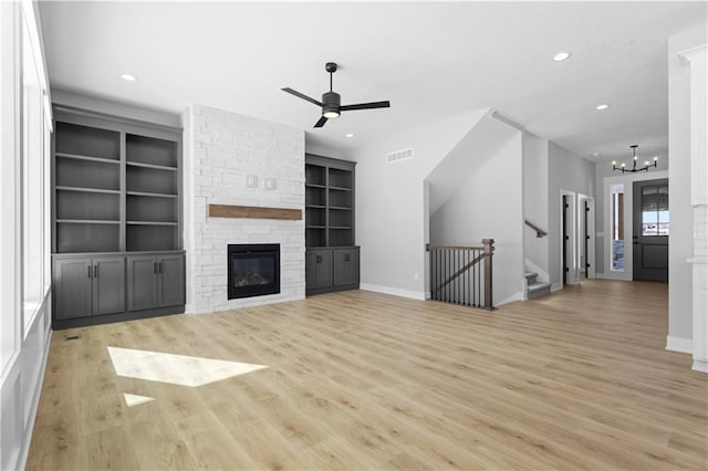 unfurnished living room featuring visible vents, ceiling fan with notable chandelier, light wood-style floors, a fireplace, and recessed lighting