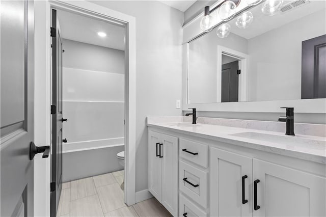 full bath with toilet, double vanity, a sink, and visible vents