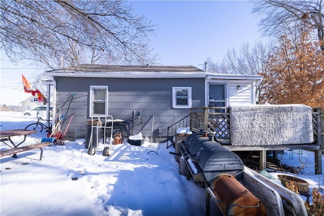 snow covered rear of property featuring a deck