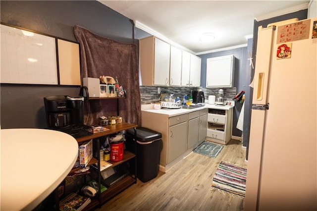 kitchen with sink, crown molding, light wood-type flooring, white refrigerator, and decorative backsplash