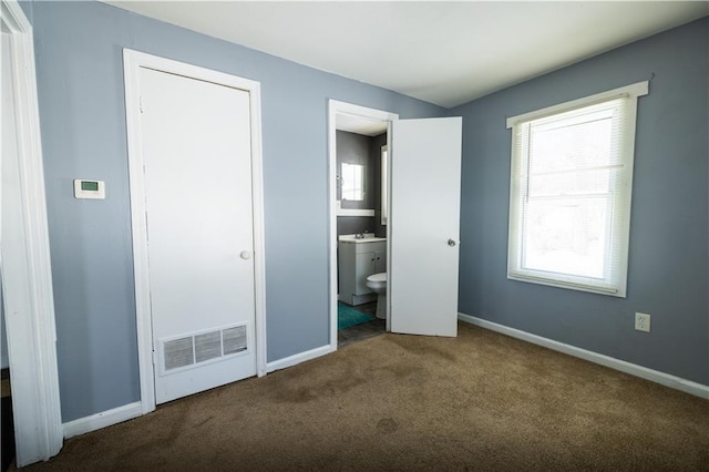 unfurnished bedroom featuring connected bathroom, carpet floors, and multiple windows