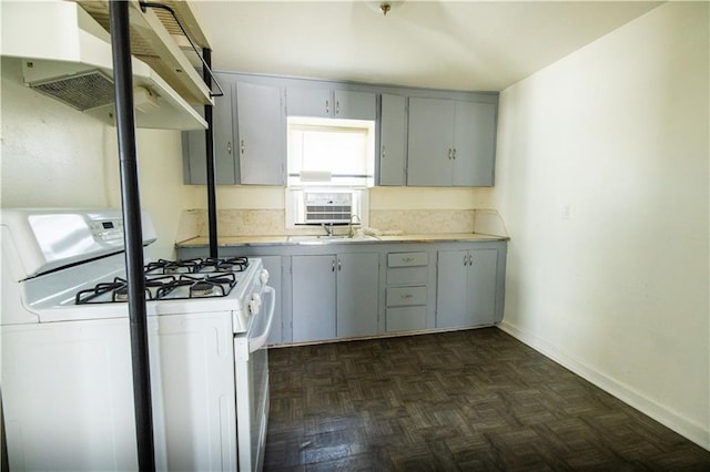 kitchen featuring gray cabinetry, extractor fan, dark parquet floors, and gas range gas stove