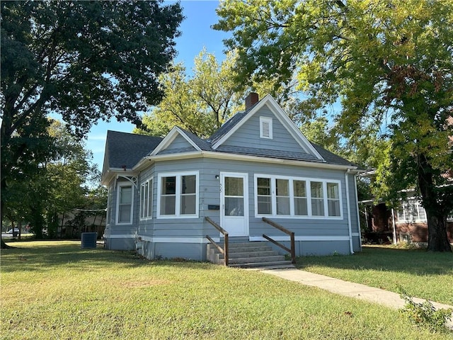 bungalow-style house with cooling unit and a front lawn