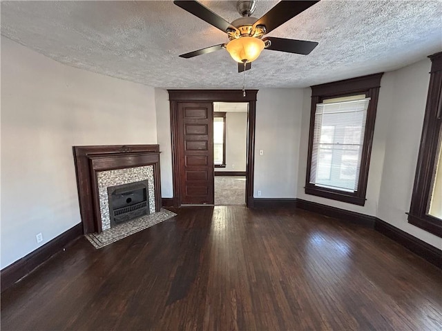 unfurnished living room featuring ceiling fan, dark wood-type flooring, a fireplace, and a textured ceiling