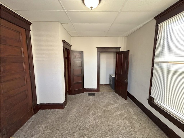 unfurnished bedroom with a paneled ceiling and light carpet