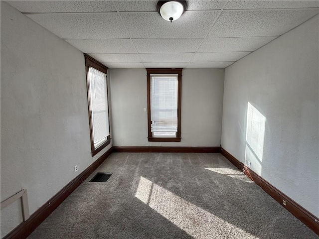 carpeted spare room with a drop ceiling