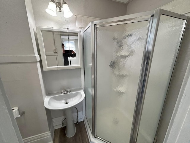 bathroom featuring a shower with shower door, hardwood / wood-style floors, and a chandelier