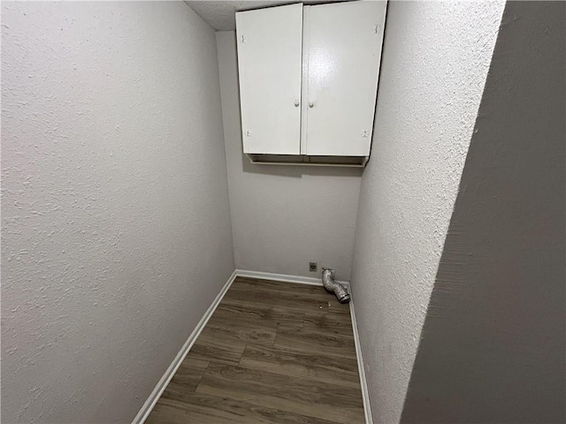 laundry room featuring cabinets, dark wood-type flooring, and a textured ceiling