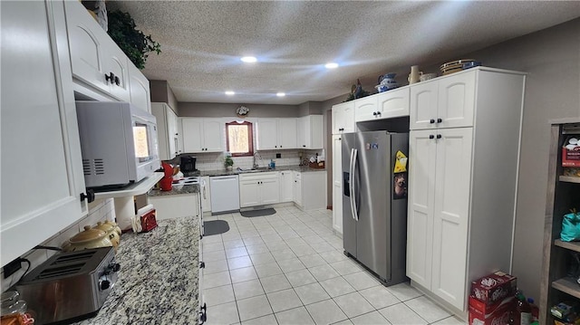 kitchen with stone counters, white cabinets, tasteful backsplash, and white appliances