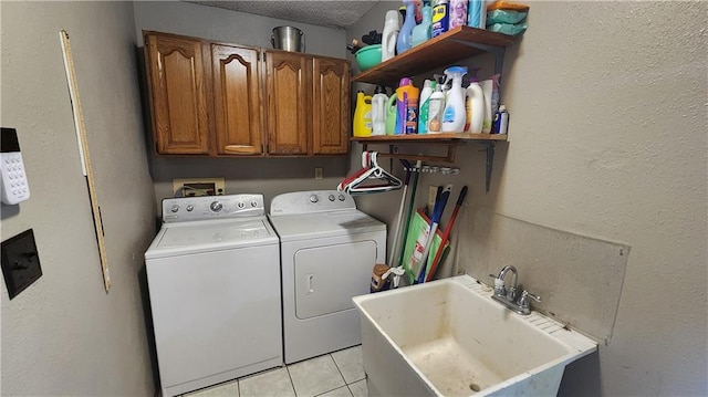 washroom with washer and dryer, light tile patterned flooring, a textured ceiling, cabinets, and sink