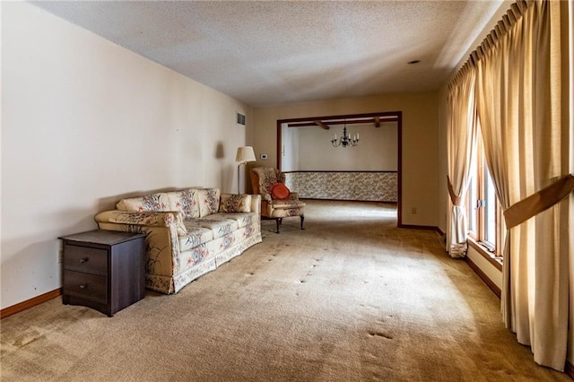 unfurnished room with light carpet, an inviting chandelier, and a textured ceiling