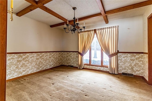 carpeted empty room featuring a notable chandelier, a textured ceiling, coffered ceiling, and beamed ceiling