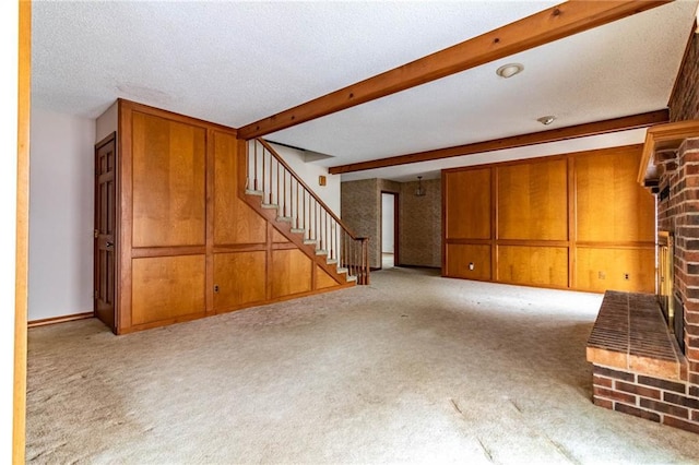 unfurnished living room featuring light carpet, a textured ceiling, wooden walls, and beamed ceiling