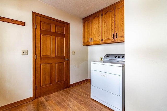 clothes washing area with washer / dryer, cabinets, a textured ceiling, and light hardwood / wood-style floors