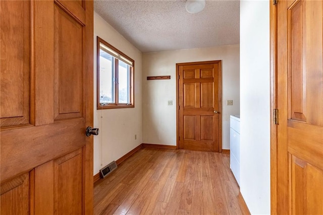 doorway to outside featuring a textured ceiling and light hardwood / wood-style flooring