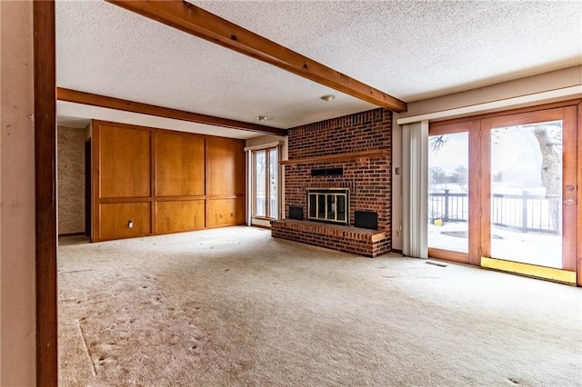 unfurnished living room with light carpet, a brick fireplace, beamed ceiling, and a textured ceiling