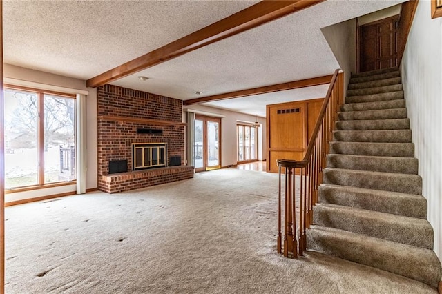 unfurnished living room with carpet flooring, a healthy amount of sunlight, beamed ceiling, and a fireplace