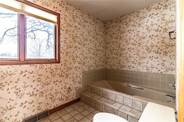 bathroom with toilet, tile patterned flooring, and a relaxing tiled tub