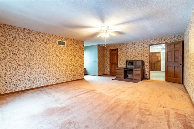 unfurnished living room with ceiling fan, light colored carpet, and a textured ceiling