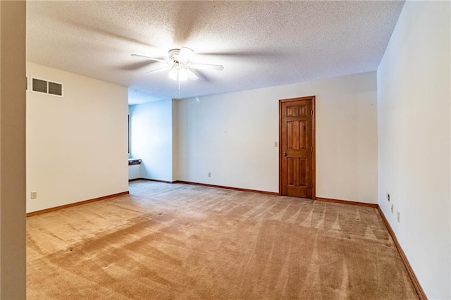 spare room with ceiling fan, a textured ceiling, and light carpet