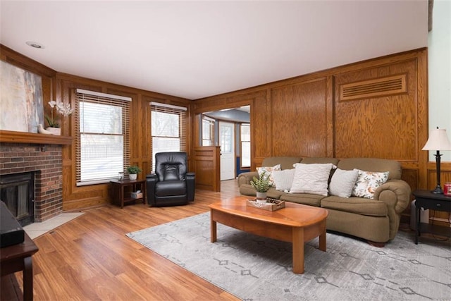 living room with a healthy amount of sunlight, light hardwood / wood-style floors, and wooden walls