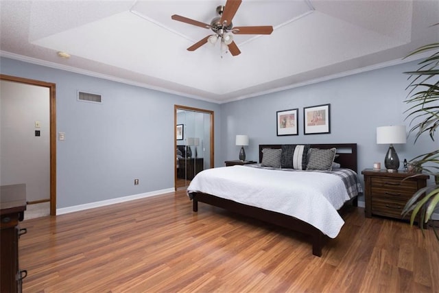 bedroom featuring ceiling fan, crown molding, a tray ceiling, and hardwood / wood-style flooring