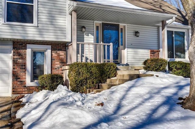 snow covered property entrance featuring a garage