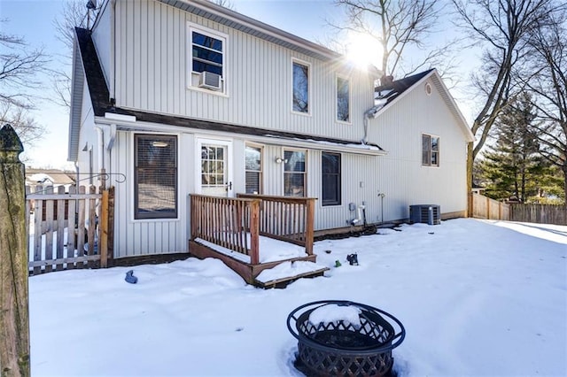 snow covered back of property featuring central air condition unit and a fire pit