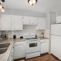 kitchen featuring pendant lighting, sink, white appliances, white cabinetry, and light stone counters