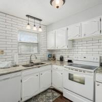 kitchen featuring white cabinets, backsplash, sink, and white appliances