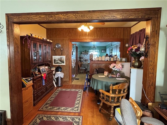 dining area featuring hardwood / wood-style flooring, a chandelier, and wooden walls